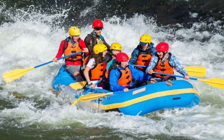 a group of gap year students paddle a raft through whitewater on an outward bound semester expedition 
